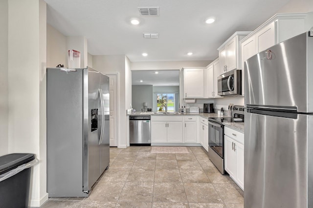 kitchen featuring white cabinetry, appliances with stainless steel finishes, sink, and light stone counters