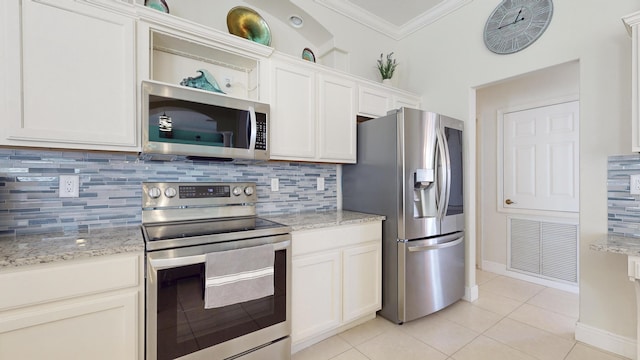 kitchen featuring light stone countertops, white cabinetry, appliances with stainless steel finishes, and light tile patterned flooring