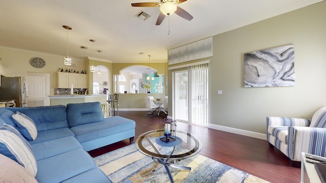 living room featuring ceiling fan, dark wood-type flooring, and crown molding