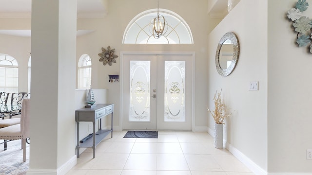 tiled foyer featuring french doors, an inviting chandelier, and a high ceiling