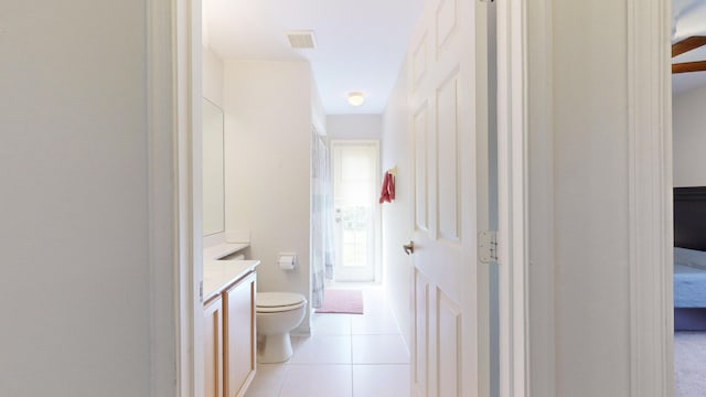 bathroom featuring toilet, tile patterned flooring, a healthy amount of sunlight, and vanity