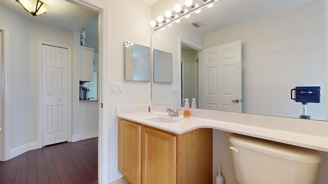 bathroom with toilet, vanity, and hardwood / wood-style floors