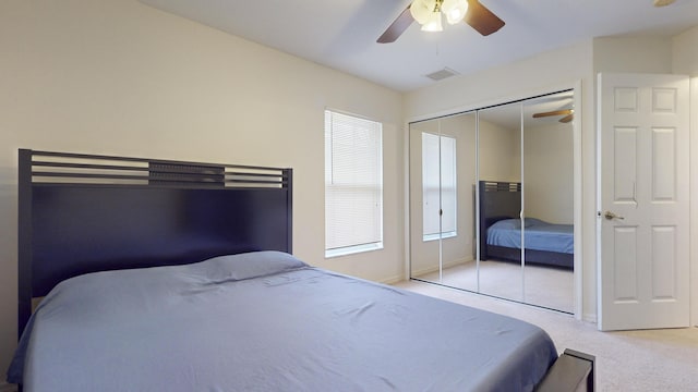 carpeted bedroom with ceiling fan, a closet, and multiple windows