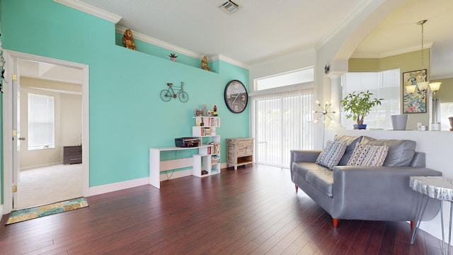 living room featuring a healthy amount of sunlight, dark wood-type flooring, crown molding, and a chandelier