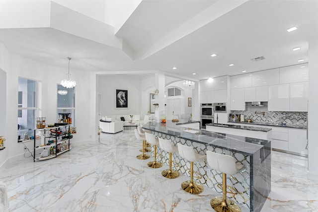 kitchen with white cabinets, decorative light fixtures, a kitchen bar, and modern cabinets