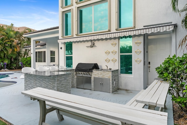 exterior space featuring exterior kitchen, a patio area, a grill, and a wet bar