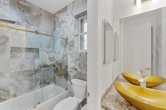 bathroom featuring toilet, tile walls, and shower / bath combination with glass door