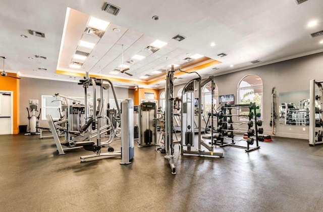 gym with a tray ceiling and ornamental molding