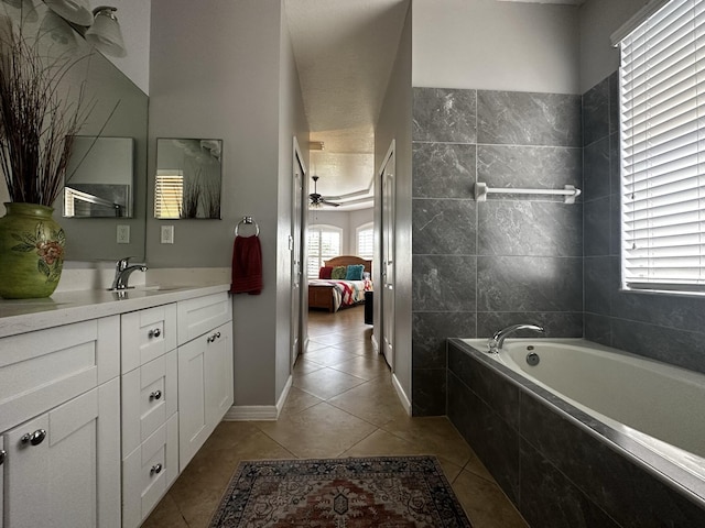 bathroom with ceiling fan, tiled tub, vanity, and tile patterned flooring