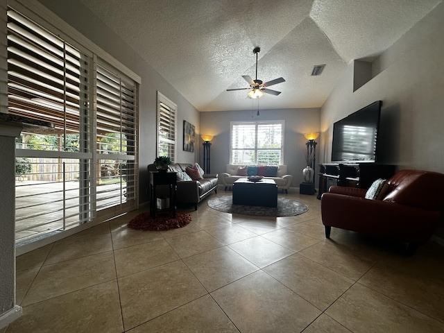 living room featuring lofted ceiling, ceiling fan, tile patterned floors, and a textured ceiling