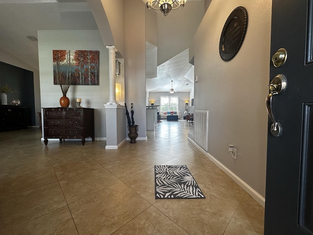 foyer with light tile patterned floors, ceiling fan with notable chandelier, and ornate columns