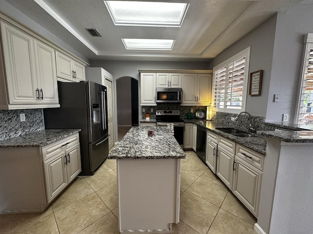 kitchen with sink, kitchen peninsula, stainless steel appliances, and dark stone countertops