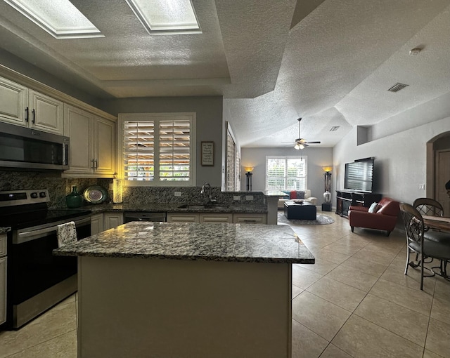 kitchen featuring light tile patterned floors, stainless steel appliances, sink, and a center island