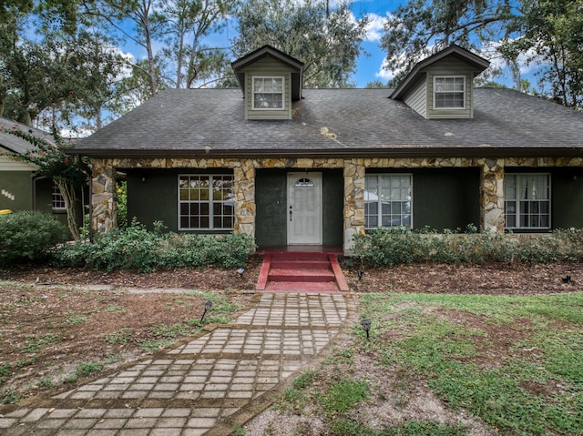 view of front facade with stone siding and a shingled roof