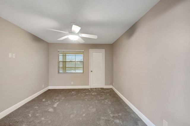 empty room with ceiling fan and dark colored carpet