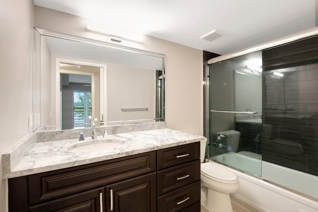 full bathroom featuring shower / bath combination with glass door, vanity, and toilet