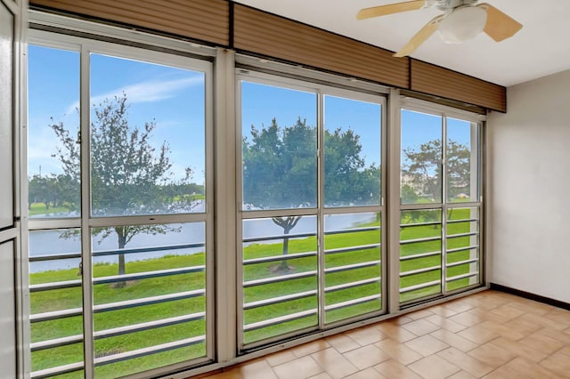 unfurnished sunroom featuring a water view and ceiling fan