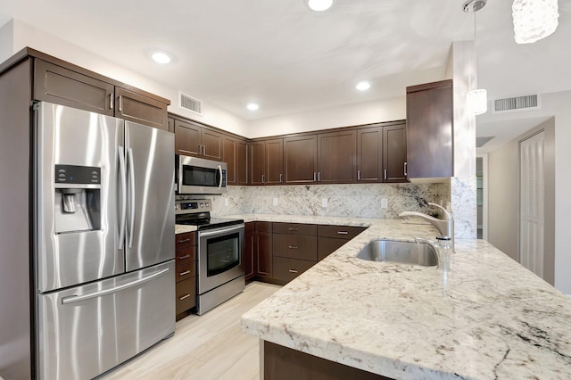 kitchen featuring appliances with stainless steel finishes, decorative light fixtures, sink, kitchen peninsula, and dark brown cabinets