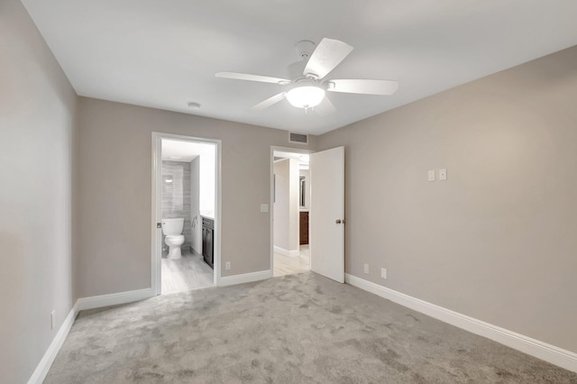 interior space with ceiling fan, light colored carpet, and ensuite bathroom