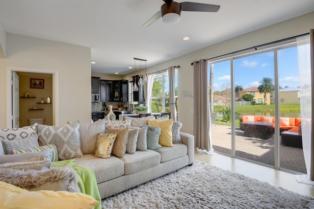 living room featuring ceiling fan and a water view