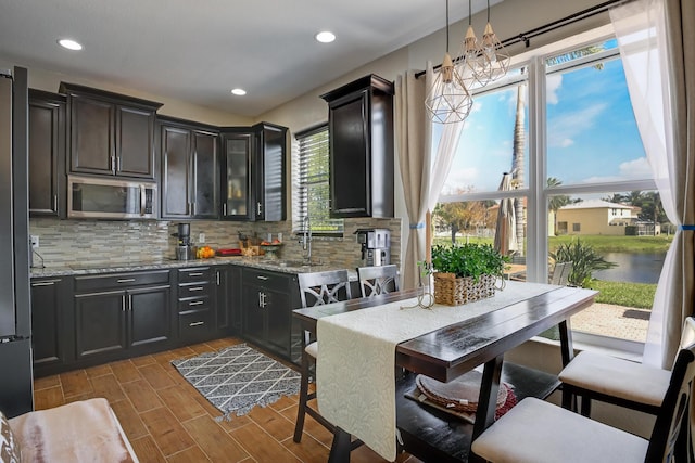 kitchen with light stone countertops, black electric stovetop, backsplash, and decorative light fixtures