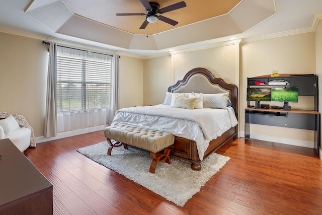 bedroom with hardwood / wood-style flooring, ceiling fan, crown molding, and a raised ceiling