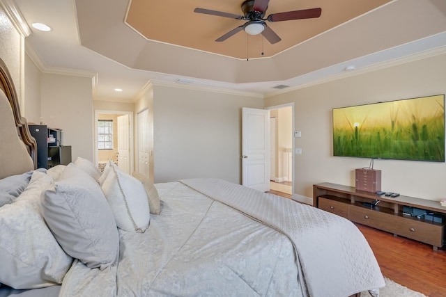 bedroom featuring ceiling fan, a tray ceiling, ornamental molding, and hardwood / wood-style flooring