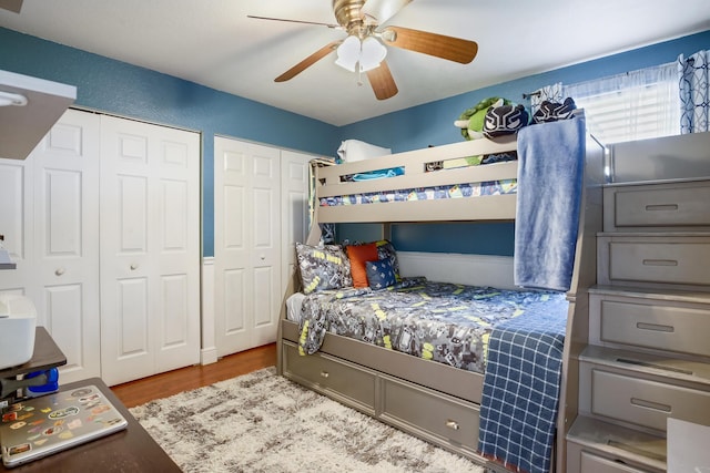 bedroom with ceiling fan, multiple closets, and light hardwood / wood-style floors