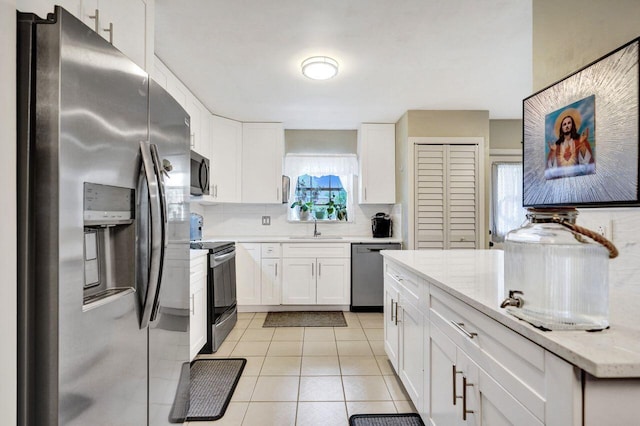 kitchen featuring stainless steel appliances, white cabinetry, and light stone counters