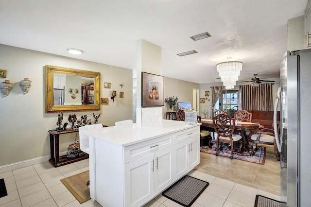 kitchen with ceiling fan with notable chandelier, decorative light fixtures, white cabinetry, stainless steel fridge, and light tile patterned floors