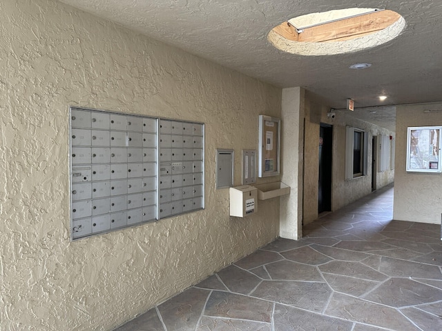 hallway with a mail area and a textured ceiling