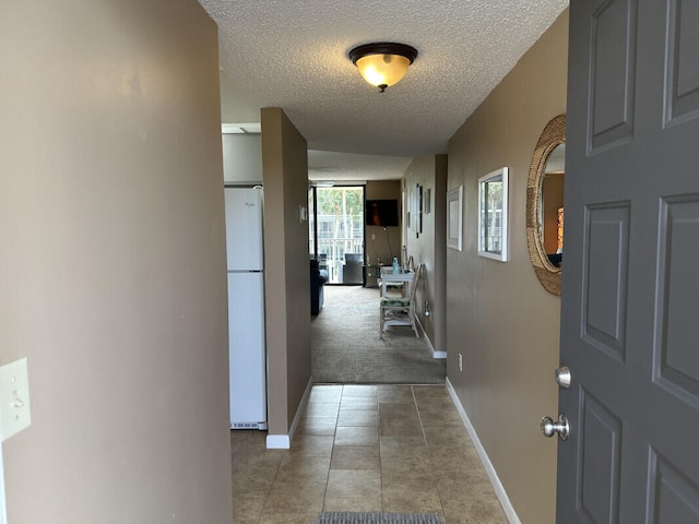 hallway featuring light colored carpet and a textured ceiling