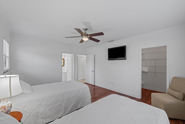 bedroom featuring crown molding, a spacious closet, dark hardwood / wood-style flooring, a closet, and ceiling fan