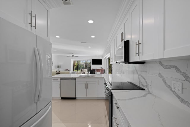 kitchen featuring light stone countertops, appliances with stainless steel finishes, white cabinetry, decorative backsplash, and ceiling fan