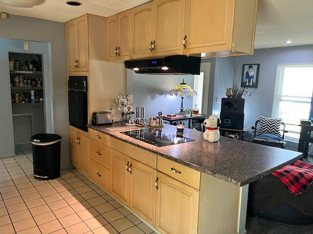 kitchen featuring black appliances, light tile patterned floors, under cabinet range hood, and light brown cabinetry