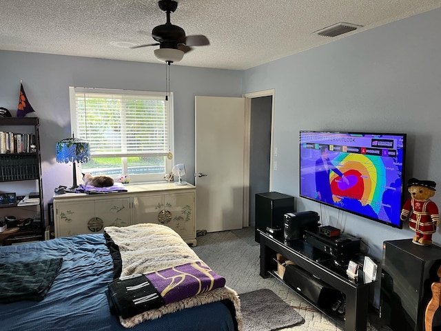 carpeted bedroom featuring visible vents, a textured ceiling, and ceiling fan