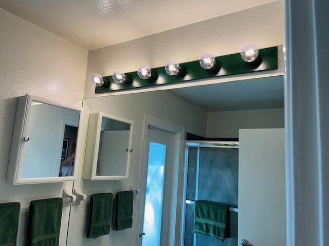 bathroom with an enclosed shower and a textured wall