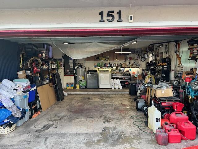 garage featuring fridge, a workshop area, washing machine and dryer, and water heater