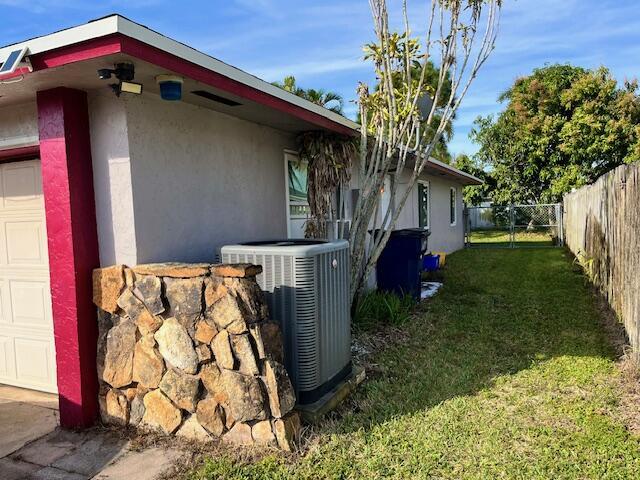 view of side of home featuring central air condition unit, a yard, stucco siding, and fence