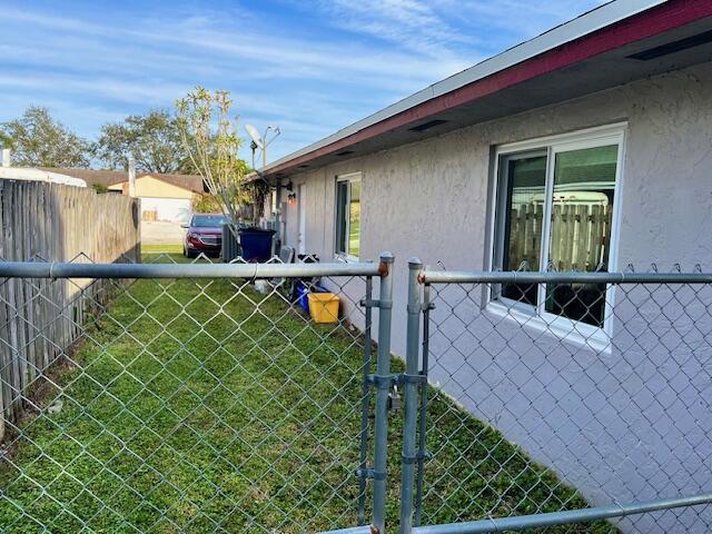 view of side of property featuring a gate, stucco siding, and fence