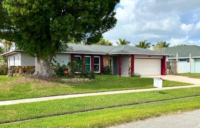 ranch-style house featuring stone siding, an attached garage, concrete driveway, and a front yard