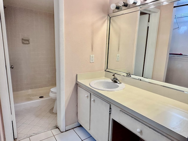 bathroom featuring vanity, toilet, tile patterned floors, and tiled shower