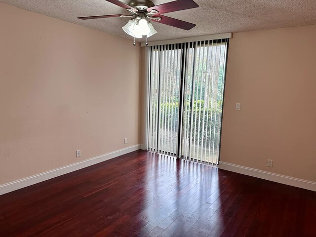 empty room featuring ceiling fan, dark wood-type flooring, and a textured ceiling