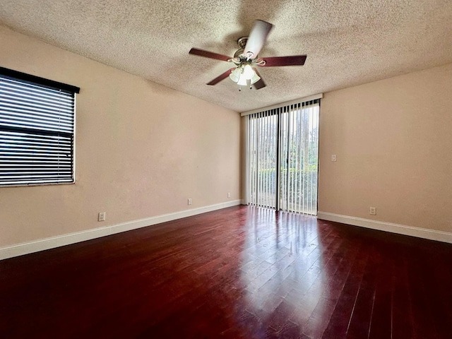 unfurnished room with dark wood finished floors, a ceiling fan, expansive windows, a textured ceiling, and baseboards