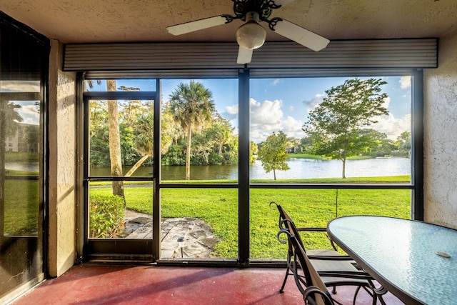 unfurnished sunroom with ceiling fan and a water view