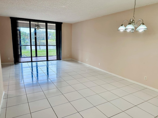 tiled spare room with floor to ceiling windows, a textured ceiling, and a chandelier