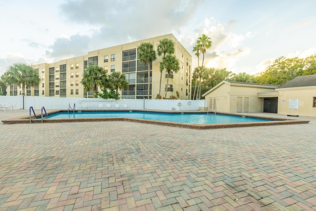 pool with a patio area and fence