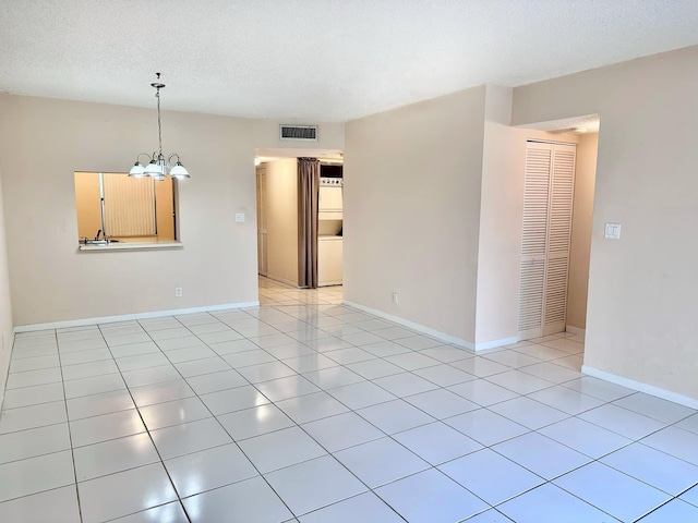 spare room with light tile patterned floors, a notable chandelier, and a textured ceiling