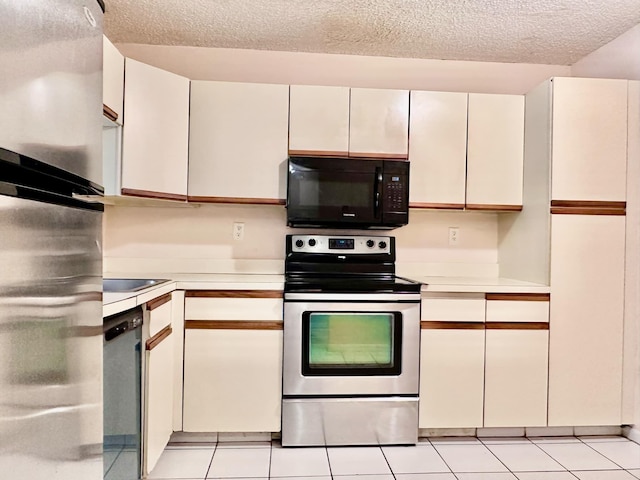 kitchen with white cabinets, light tile patterned floors, stainless steel appliances, and a textured ceiling