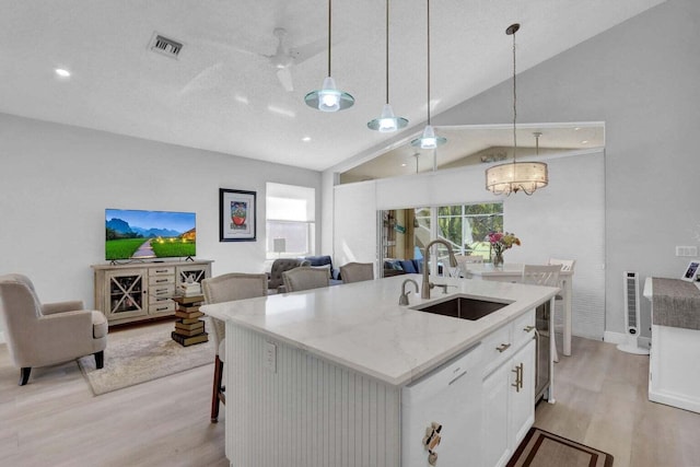 kitchen featuring pendant lighting, white cabinetry, sink, a kitchen breakfast bar, and a kitchen island with sink